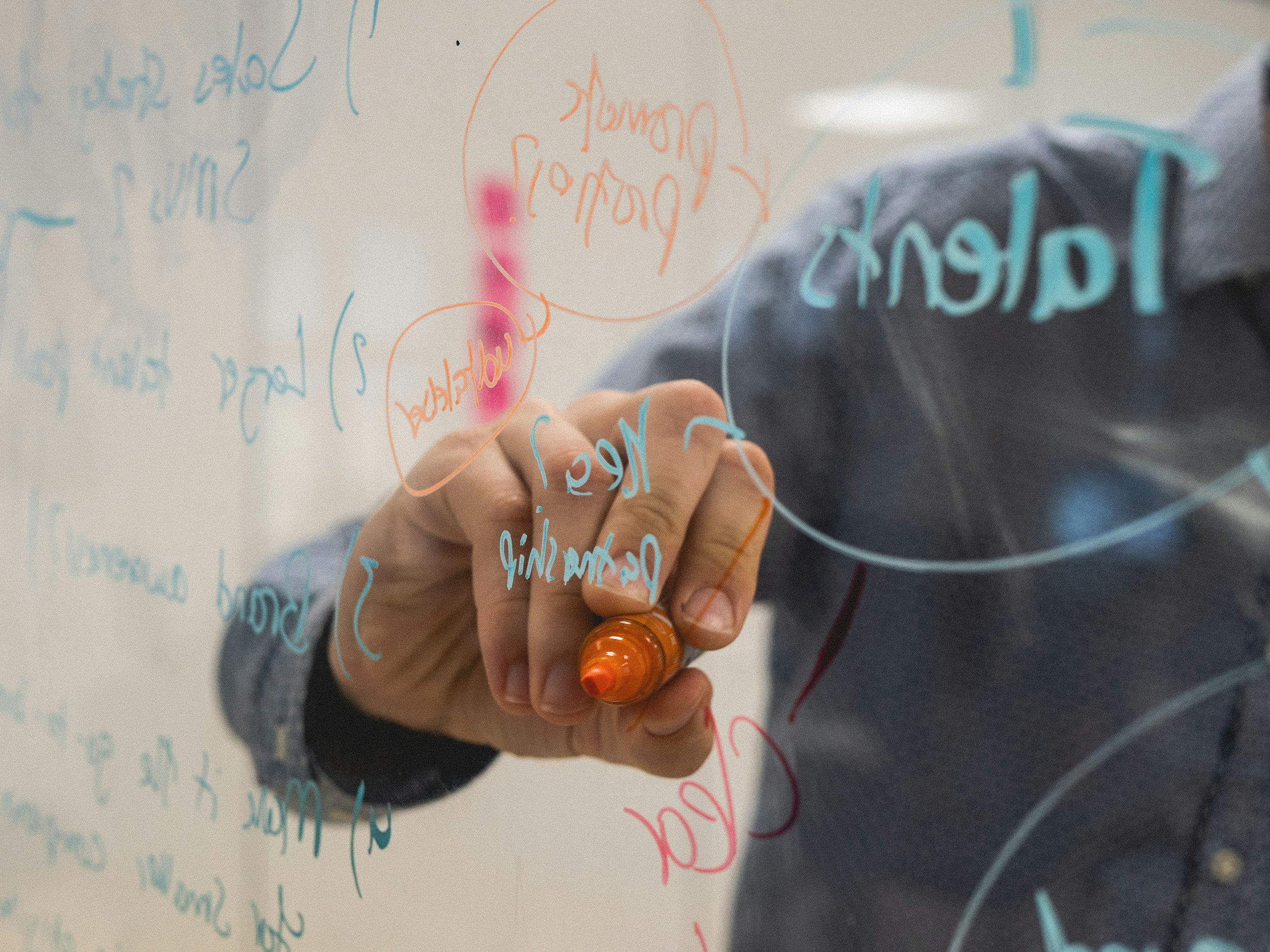 close up of hand writing on board with marker