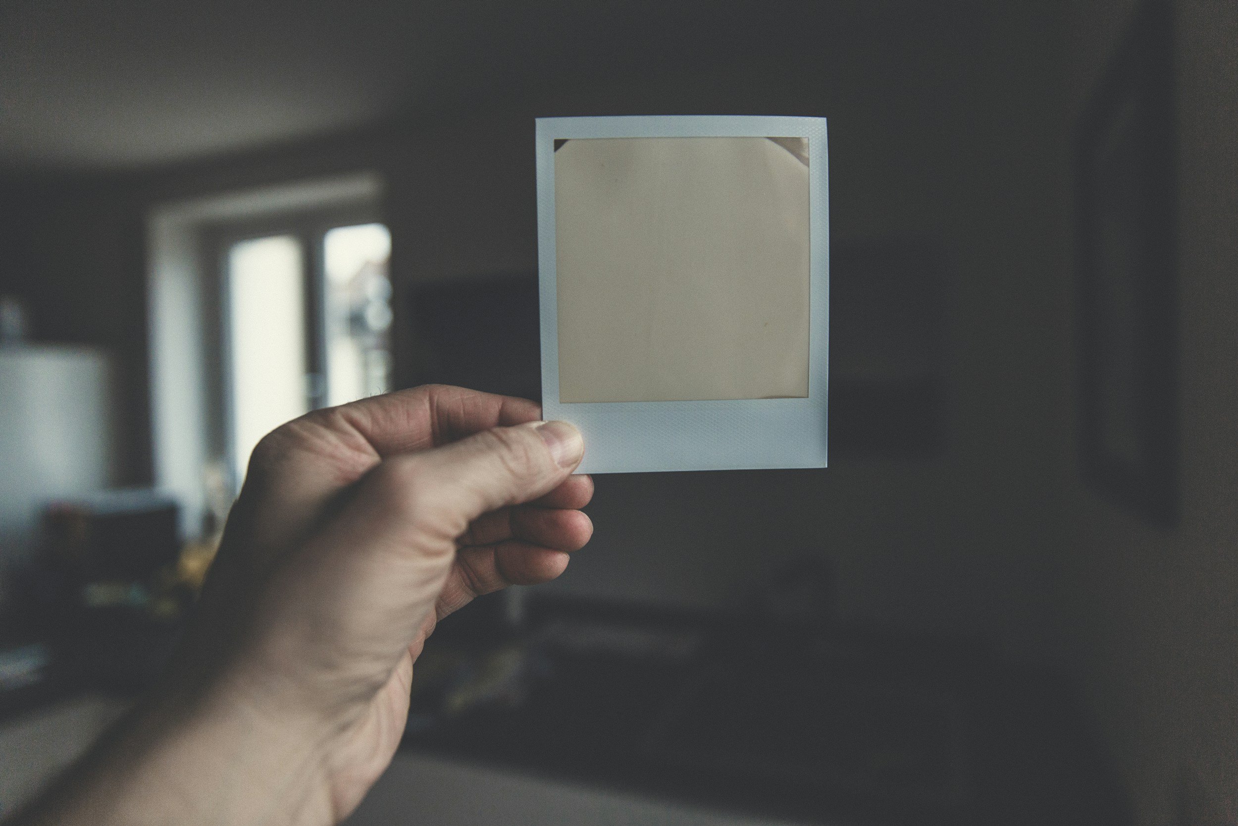close up of hand holding an undeveloped polaroid picture